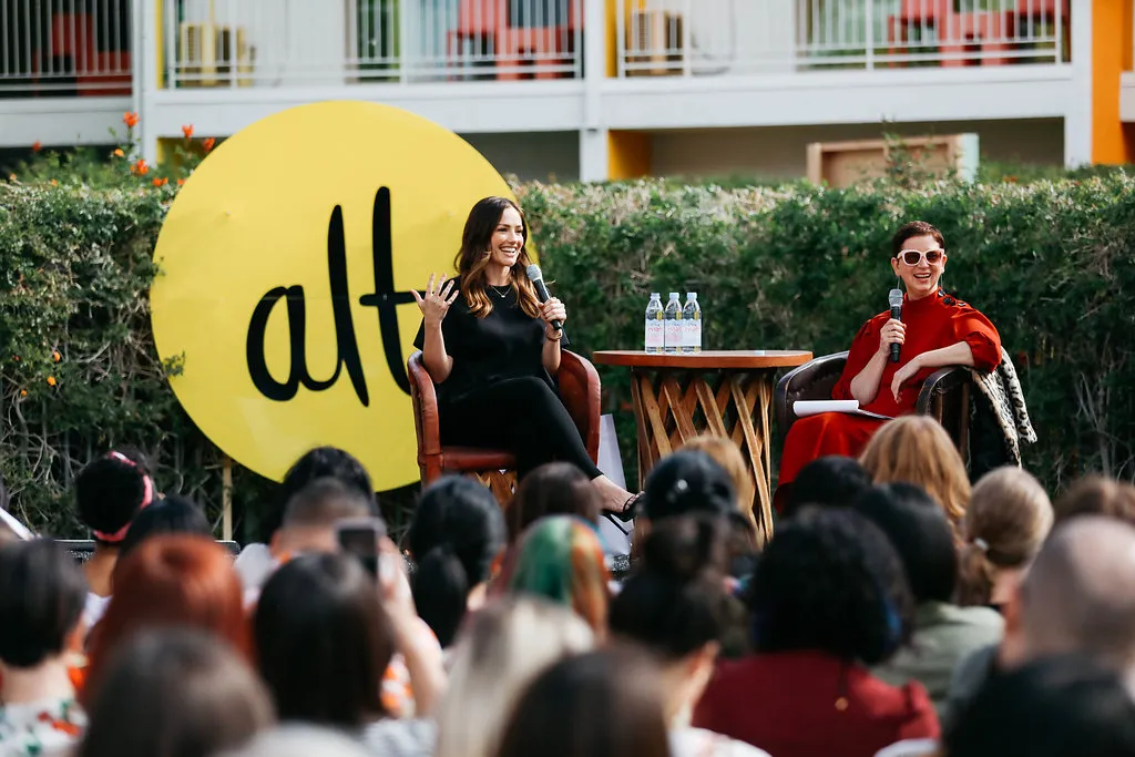 Live panel discussion at Alt Summit with speakers on stage in front of the Alt logo and an audience.